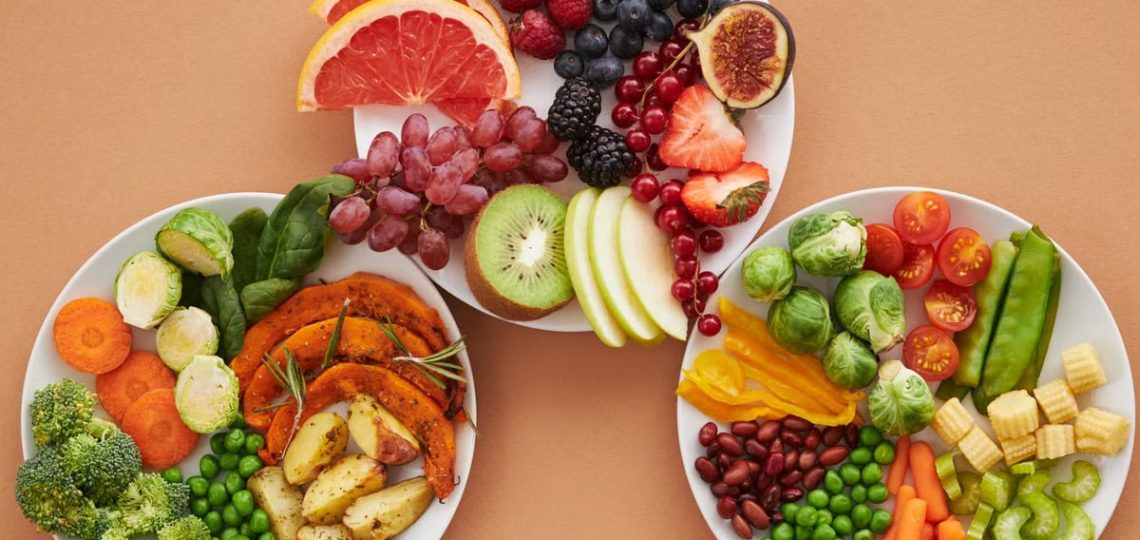 Top view of vibrant plates of fresh fruits and vegetables, perfect for a healthy lifestyle.