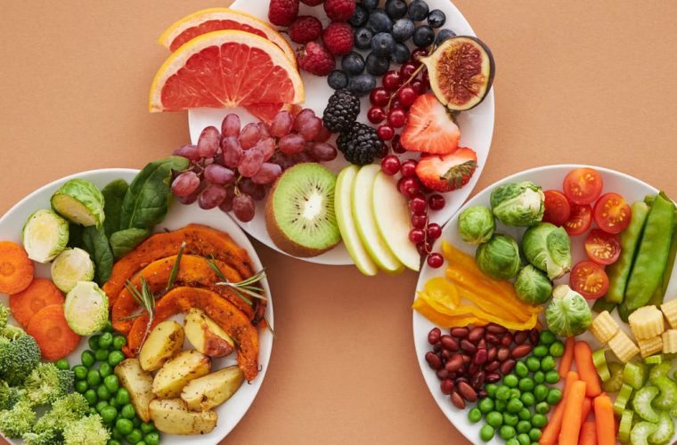 Top view of vibrant plates of fresh fruits and vegetables, perfect for a healthy lifestyle.