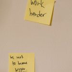 Yellow sticky notes with motivational phrases posted on a white wall, inspiring action.