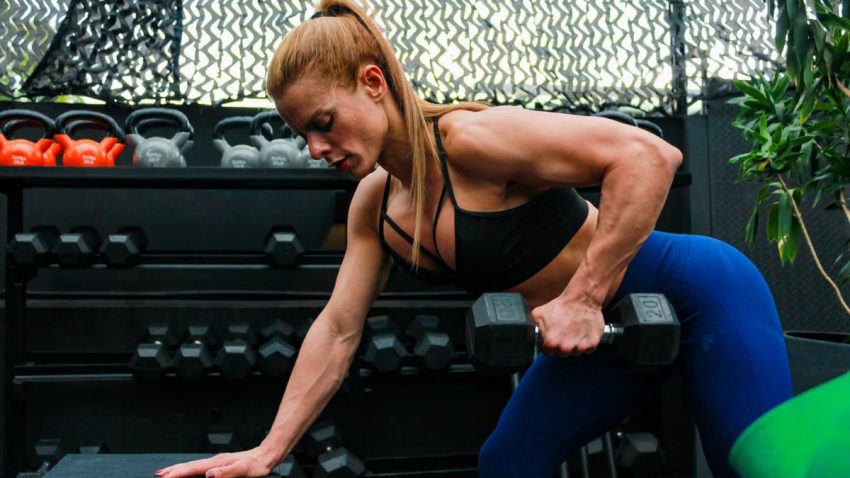 A fit woman lifting weights in a gym setting illustrating determination and strength.